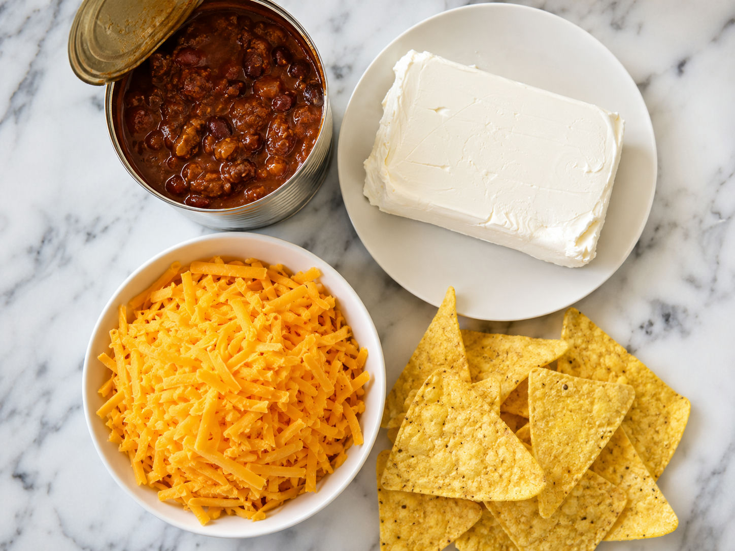 Cream cheese, canned chili, shredded cheddar, and corn chips for chili cheese dip