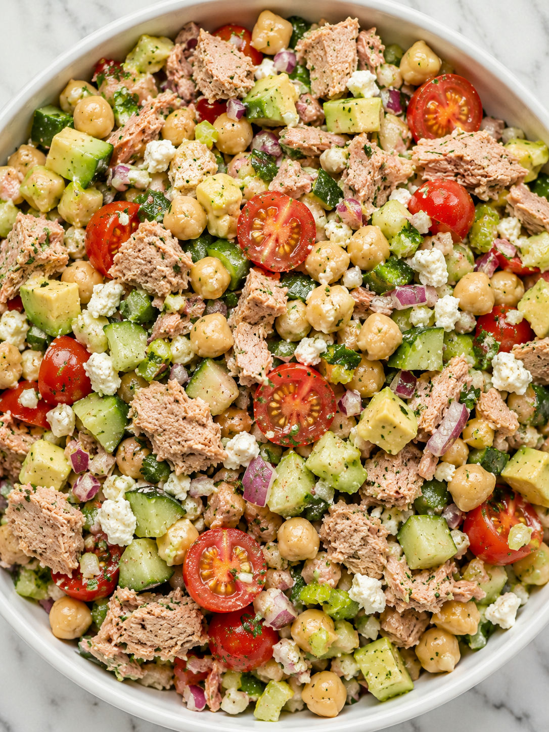 Top-down tuna chickpea feta salad with avocado, tomatoes, and parsley