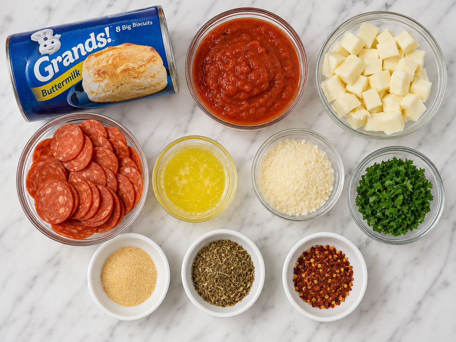 Ingredients for pizza bombs with biscuit dough, mozzarella, pepperoni, and sauce