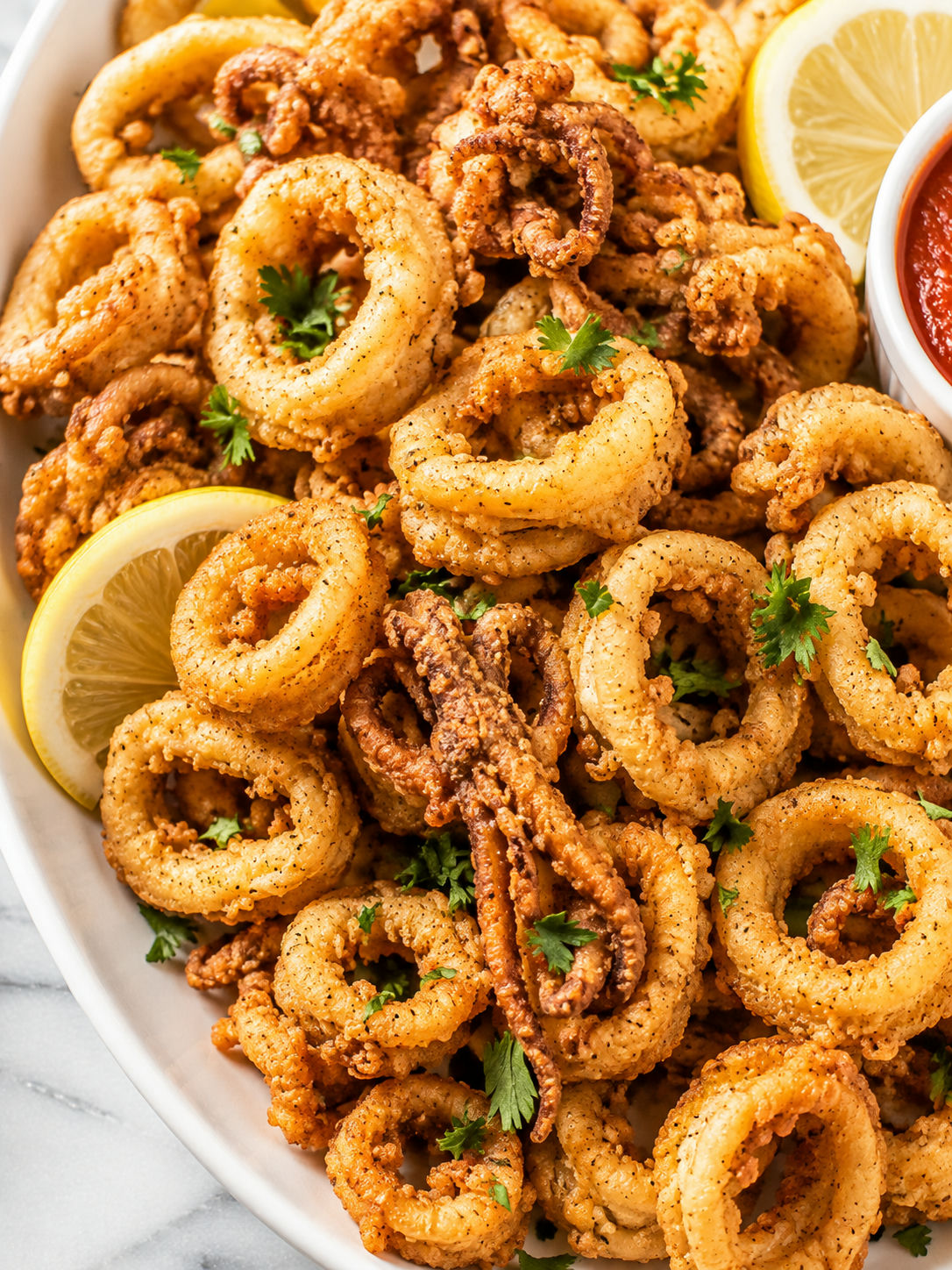 Golden fried calamari with lemon wedges, parsley, and marinara