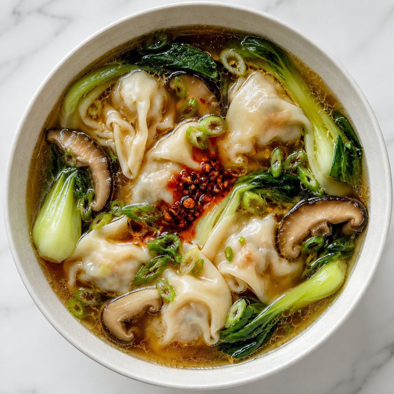 Dumpling soup with bok choy, shiitake mushrooms, green onions, and chili crisp