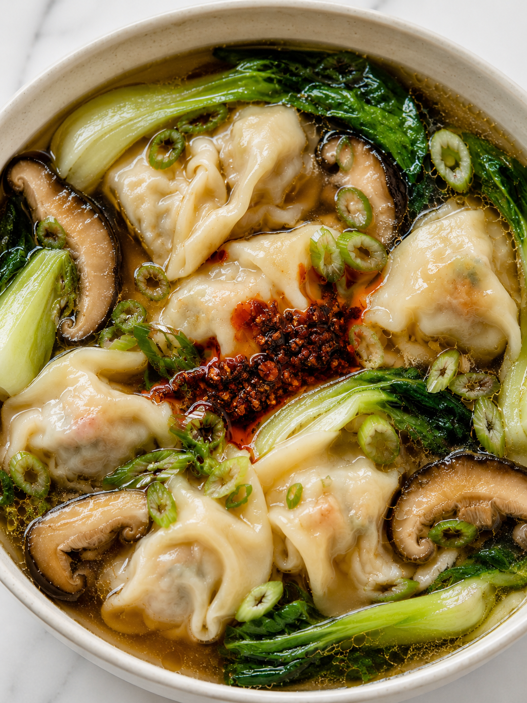 Tender dumpling soup with bok choy, shiitake mushrooms, green onions, and chili crisp