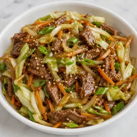 Beef cabbage stir-fry with carrots, green onions, and sesame seeds