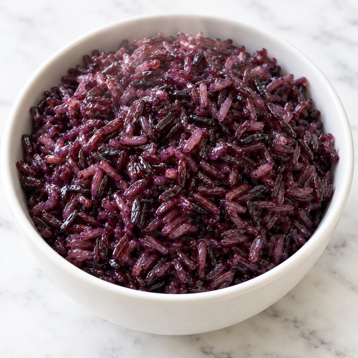 Cooked purple rice in a white bowl with glossy violet grains