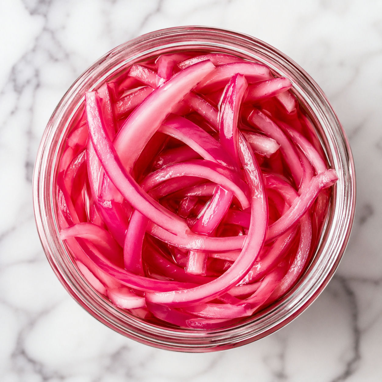Bright pickled red onions in a glass jar with glossy pink brine