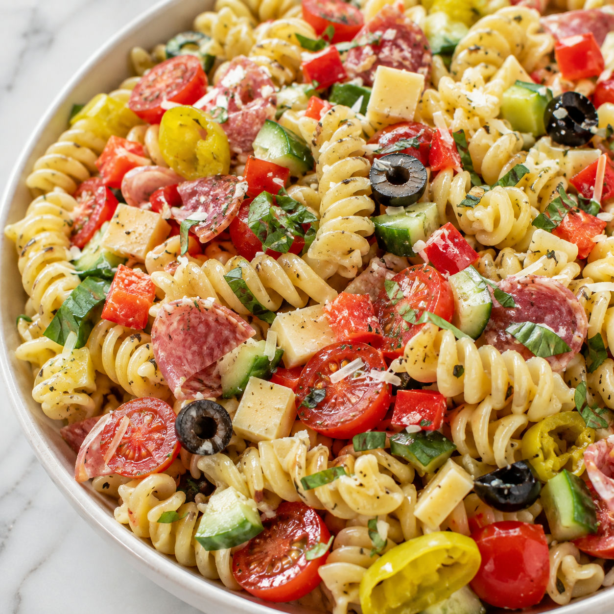 Loaded rotini pasta salad with vegetables, salami, cheese, and basil