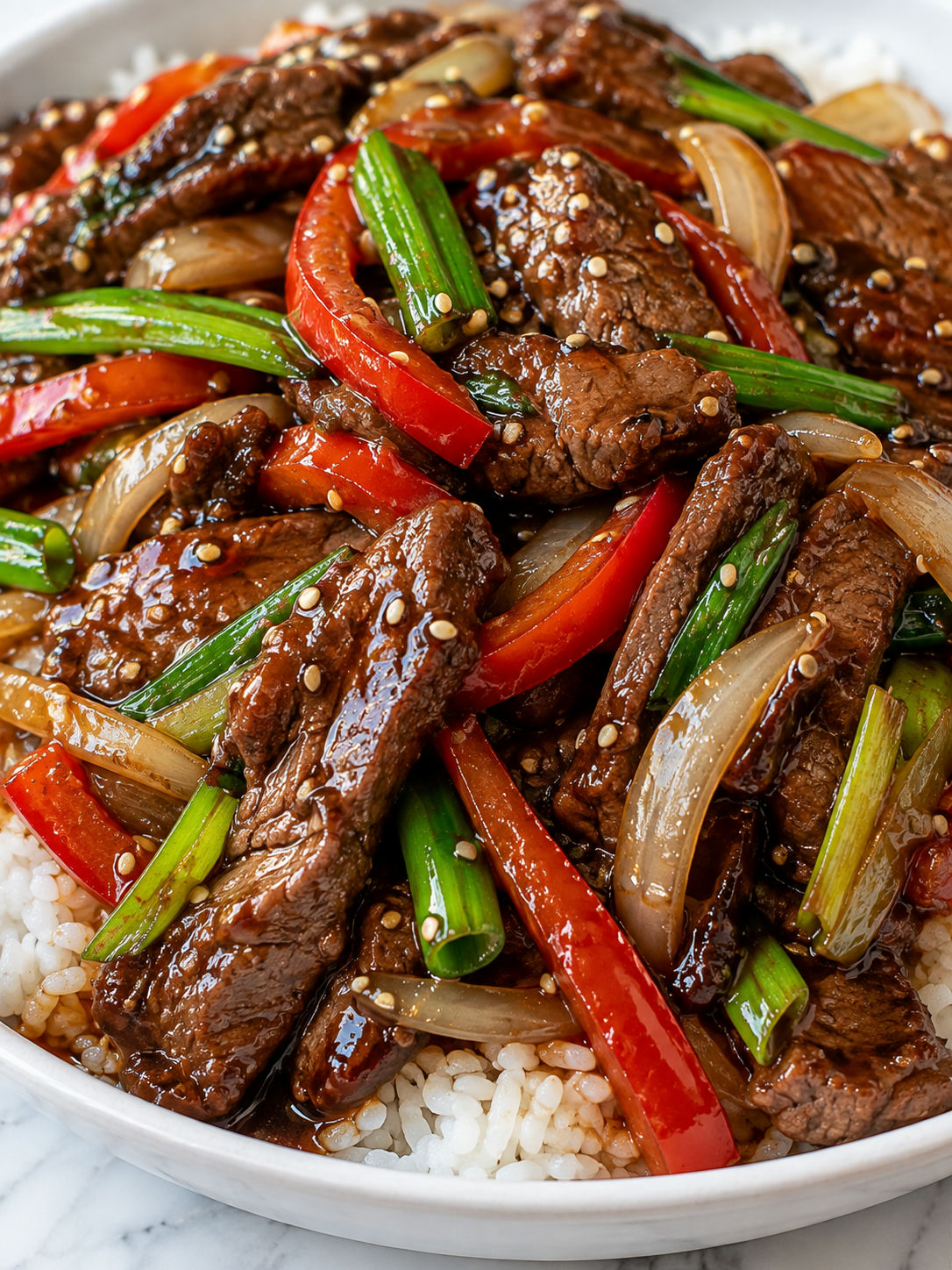 Glossy Asian beef stir-fry with peppers, scallions, sesame, and rice