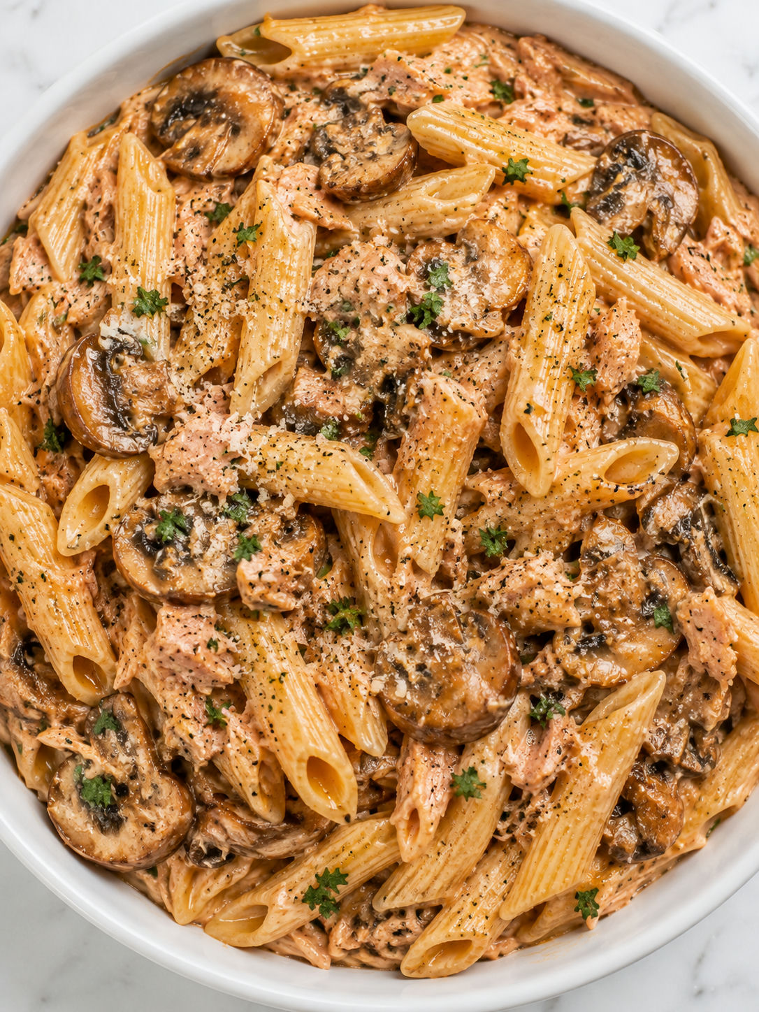 Top-down bowl of creamy tuna mushroom pasta with parsley and Parmesan