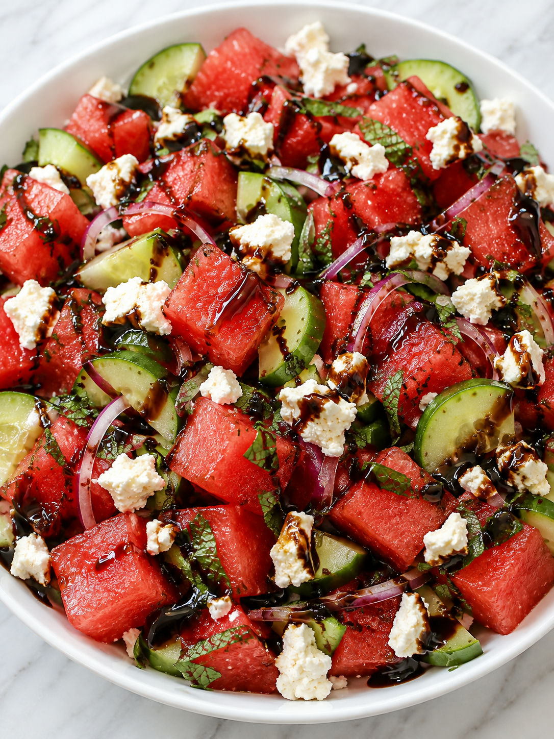 Watermelon feta salad with glossy balsamic glaze in a white bowl