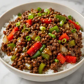 Ground beef pepper stir-fry over rice with green onions and sesame seeds